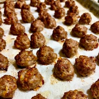 Close up photo of mini meatballs, fully cooked on a baking sheet.