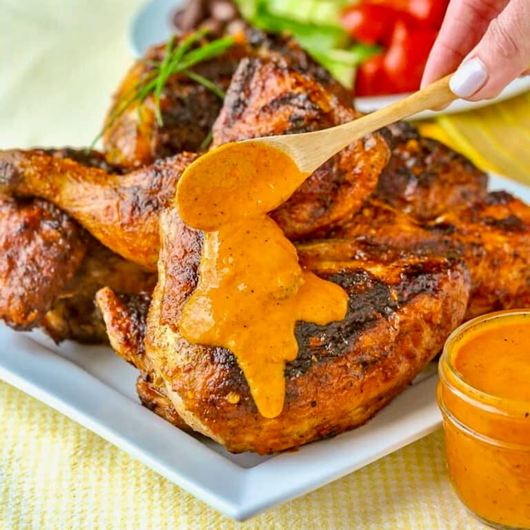 Peri Peri Sauce on Portuguese Chicken with sauce being spooned onto cooked chicken.