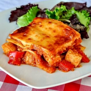 Chicken Parmesan Lasagna photo of single serving with salad on a white plate.