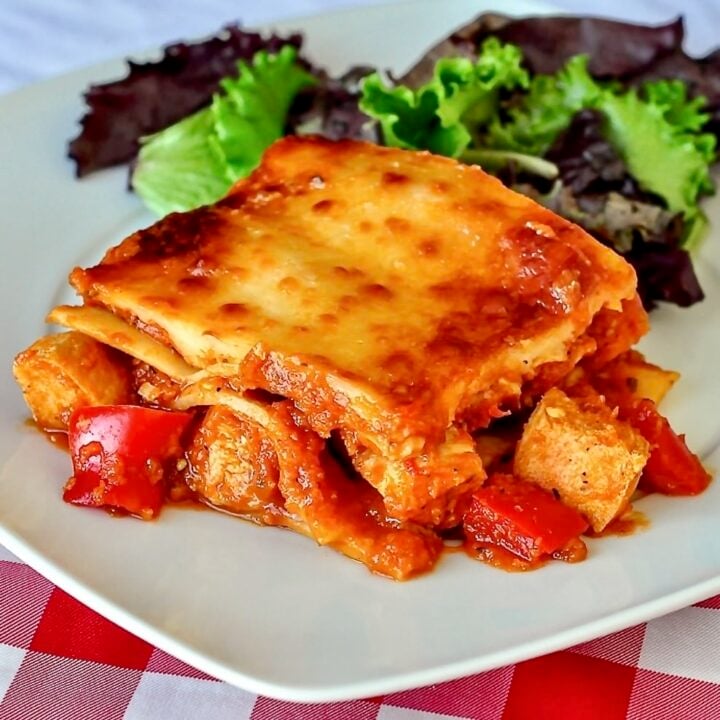Chicken Parmesan Lasagna photo of single serving with salad on a white plate.