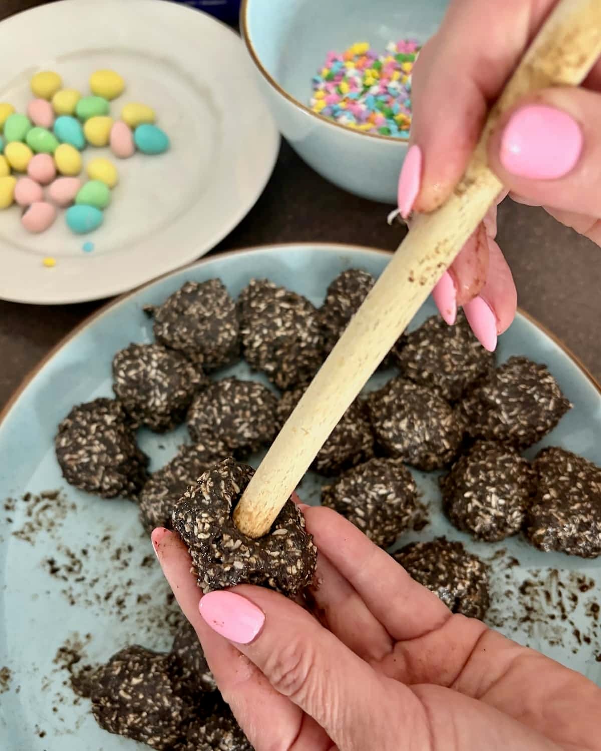 Photo of wooden spoon handle making an indent into the cookie ball.