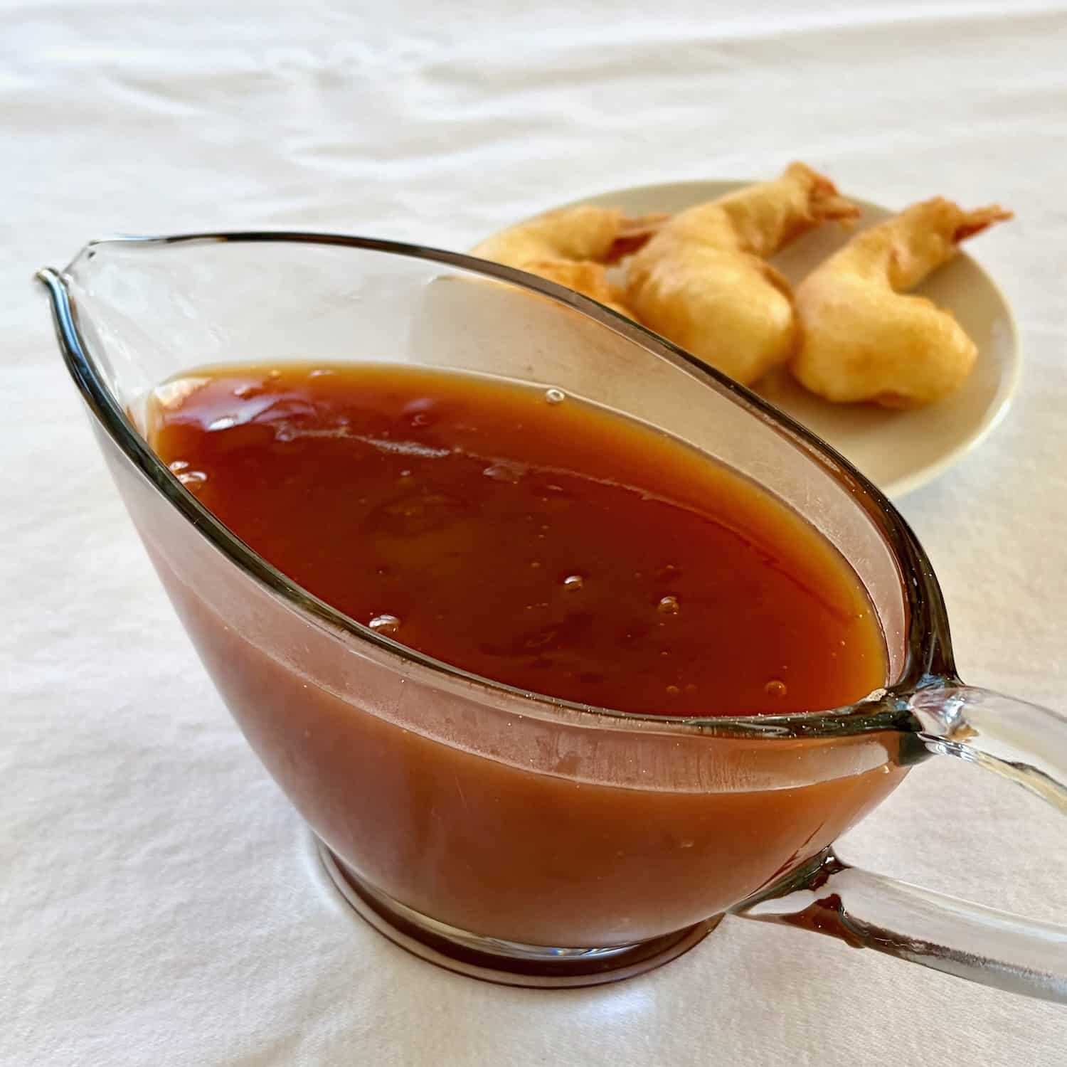 Photo of sweet and sour sauce in a clar sauce boat.