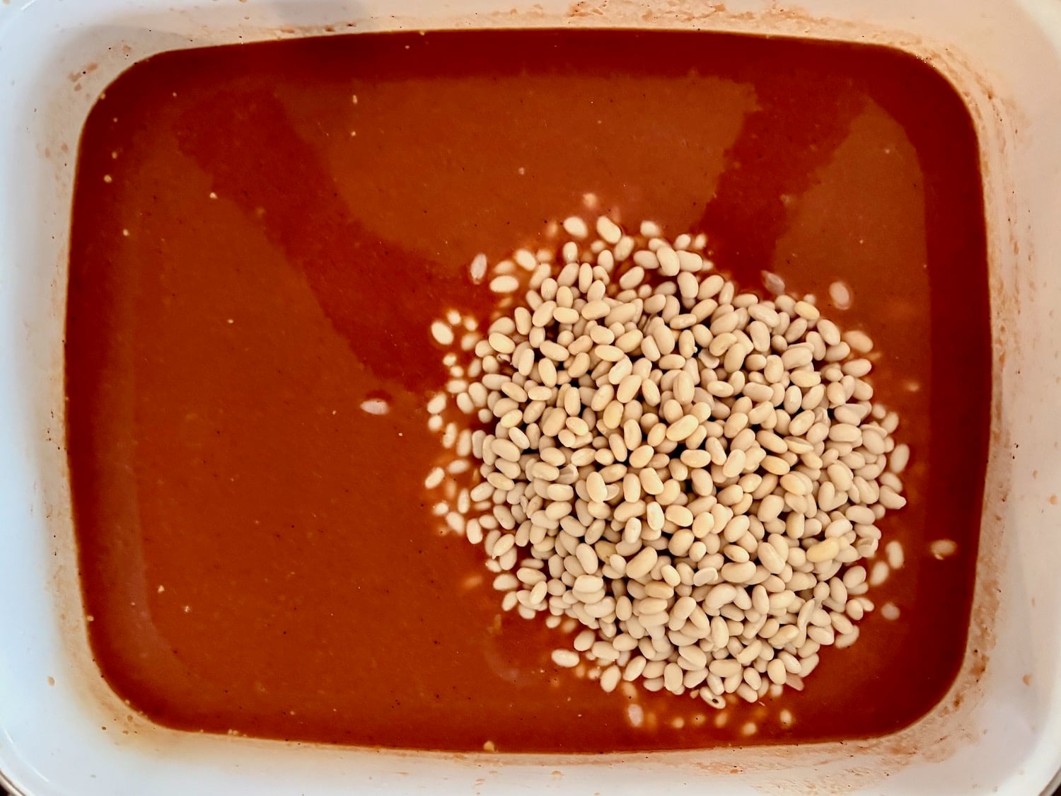 Photos of beans being added to the sauce for Beans and Weiners.