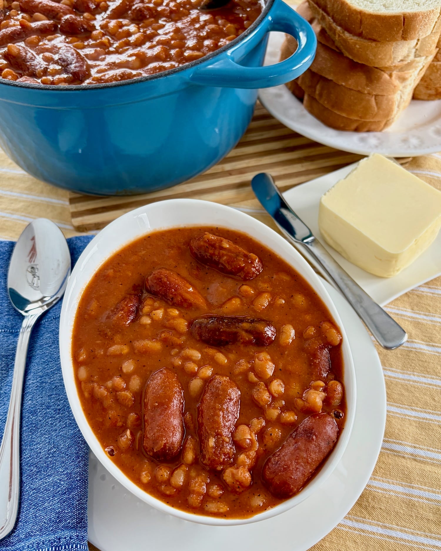 Overhead shot of one serving of Overhead shot of a dutch oven containing the finished Beans and Weiners.in a white bowl.
