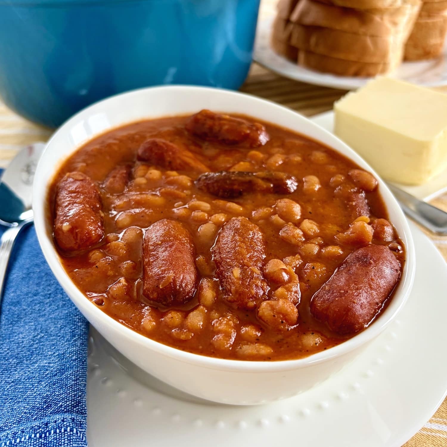 Beans and weiners close up photo of one serving with blue dutch oven in the background.