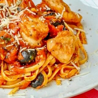 Pan Fried Cod Puttanesca close up photo on a white plate