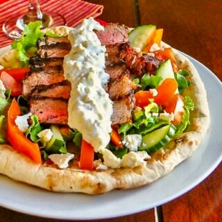 Souvlaki Steak shown served with Greek salad on homemade flatbread.