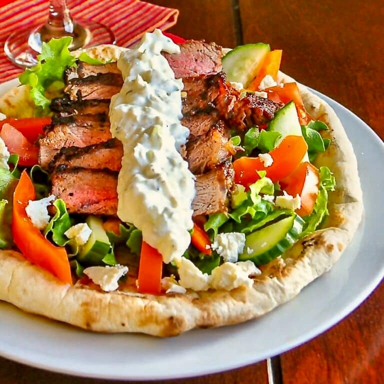 Souvlaki Steak shown served with Greek salad on homemade flatbread.