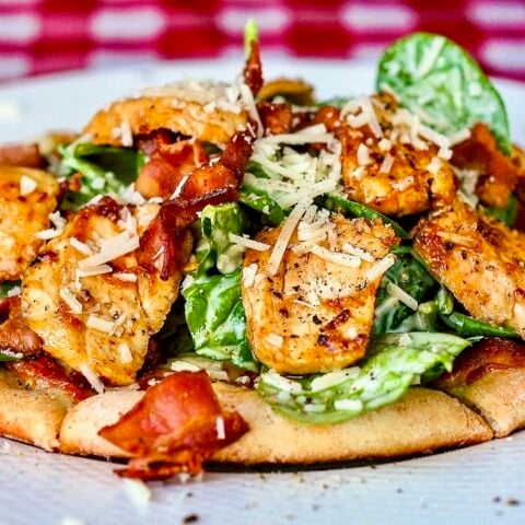 Spinach Caesar Salad on oat bran pizza on a White plate.