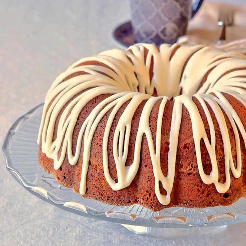 Cinnamon Roll Cake photo iof uncut cake in a glass pedestal.