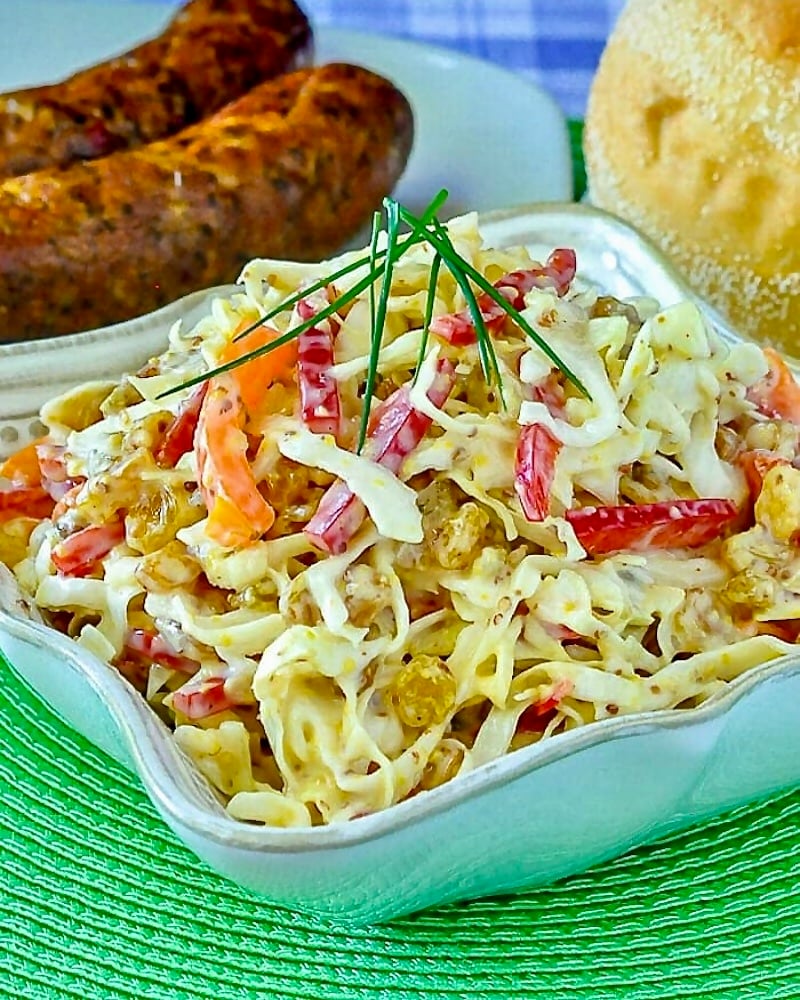 Dijon Coleslaw with sausages and bread rolls in background.