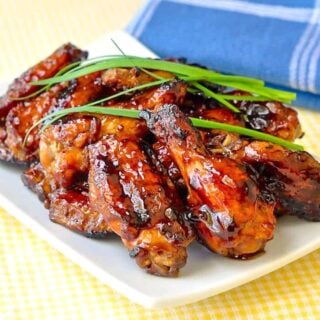 Grilled Honey Barbecue Wings, beautifully glazed sticky wings photographed on a white platter with chive garnish