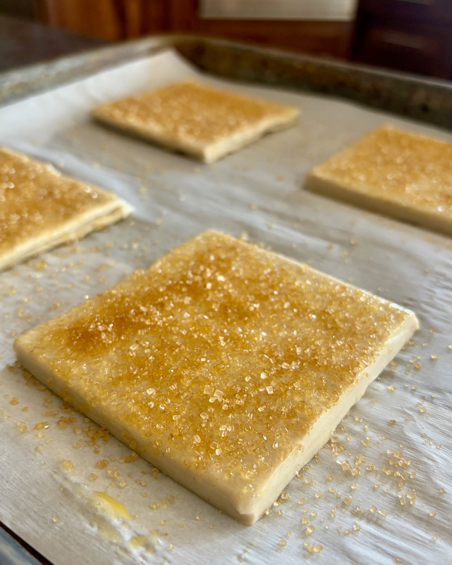 Coarse sugar atop squares of puff pastry.