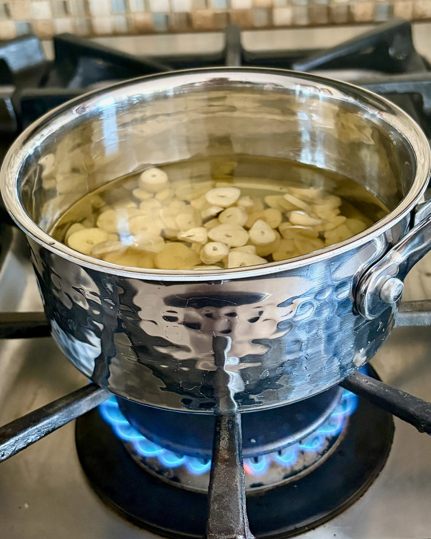 Photo of garlic and oil over low gas flame.