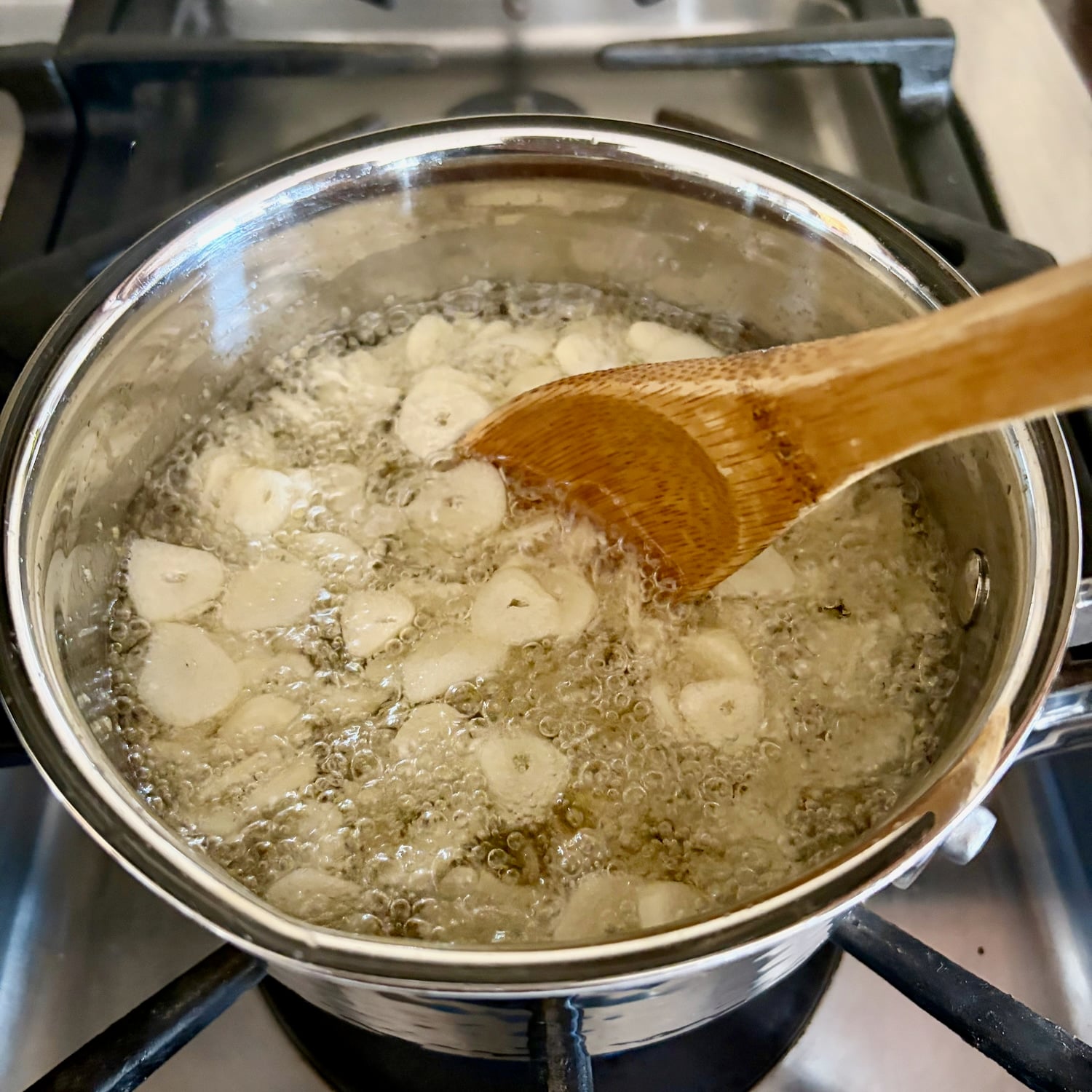 photo if wooden spoon stirring. garlic in oil