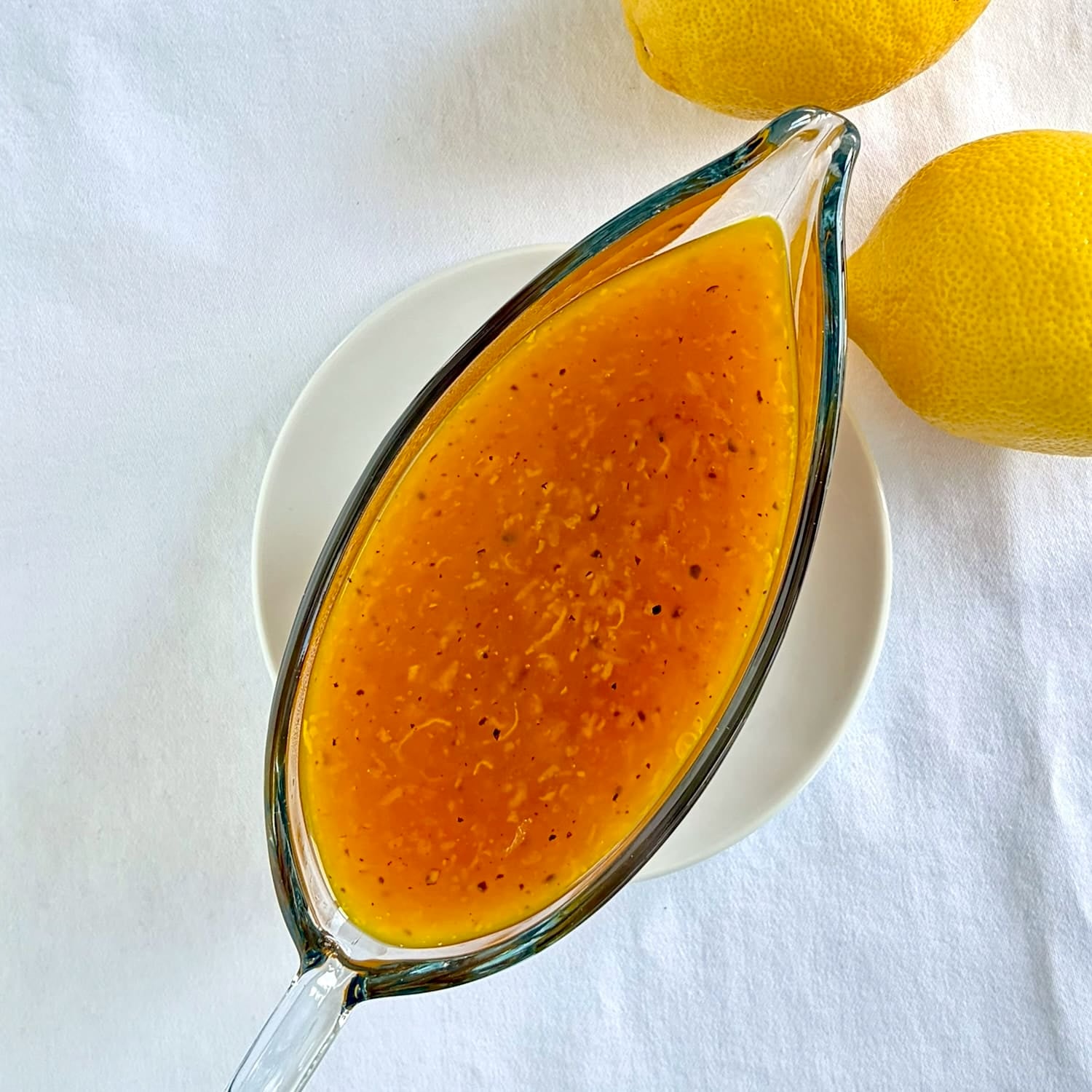 Overhead close up photo of the best lemon sauce in a clear glass serving boat.