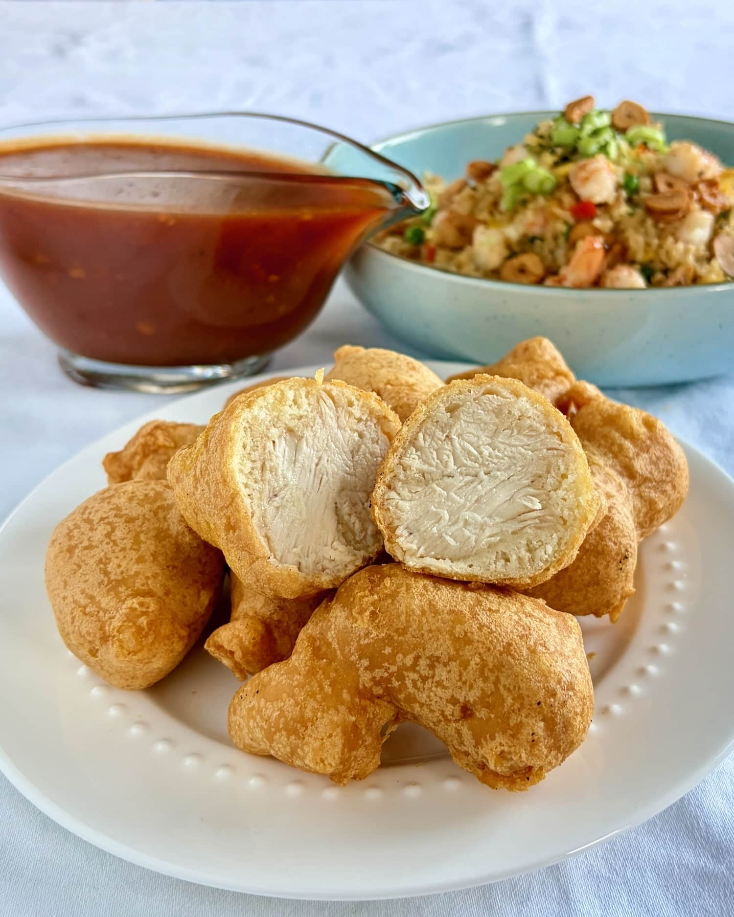 Chinese Chicken balls on a plate with one cut in half to reveal the chicken inside.