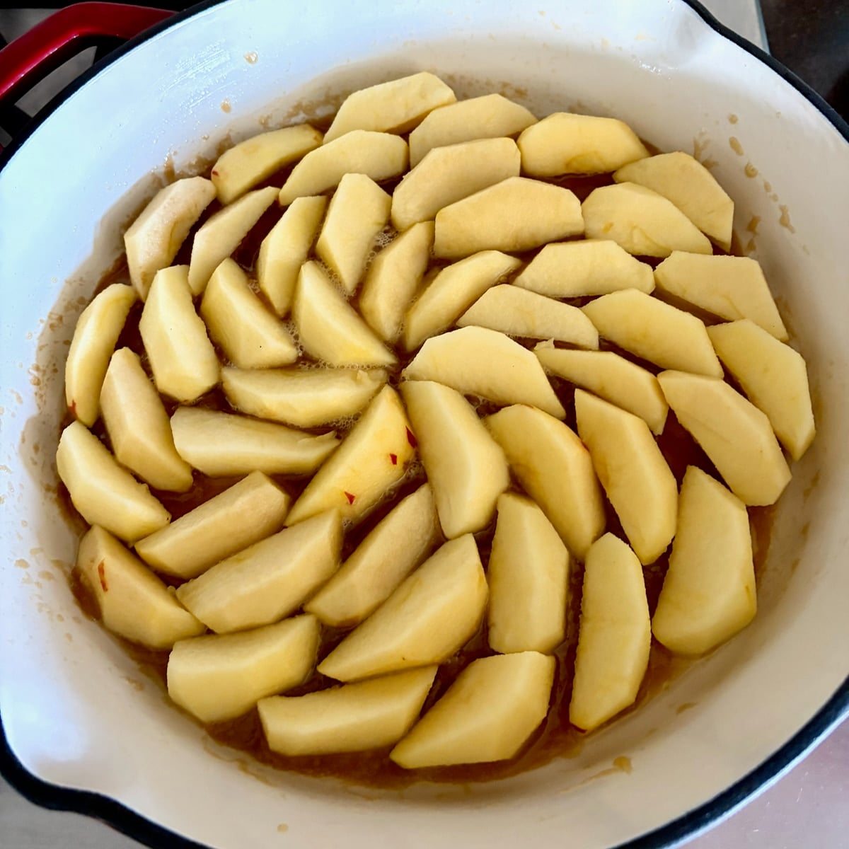 Apple slices arranged over the caramel in a skillet