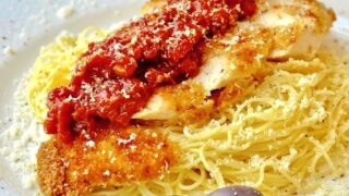 Low Fat Baked Panko Chicken Parmesan plated on a bed of spaghetti