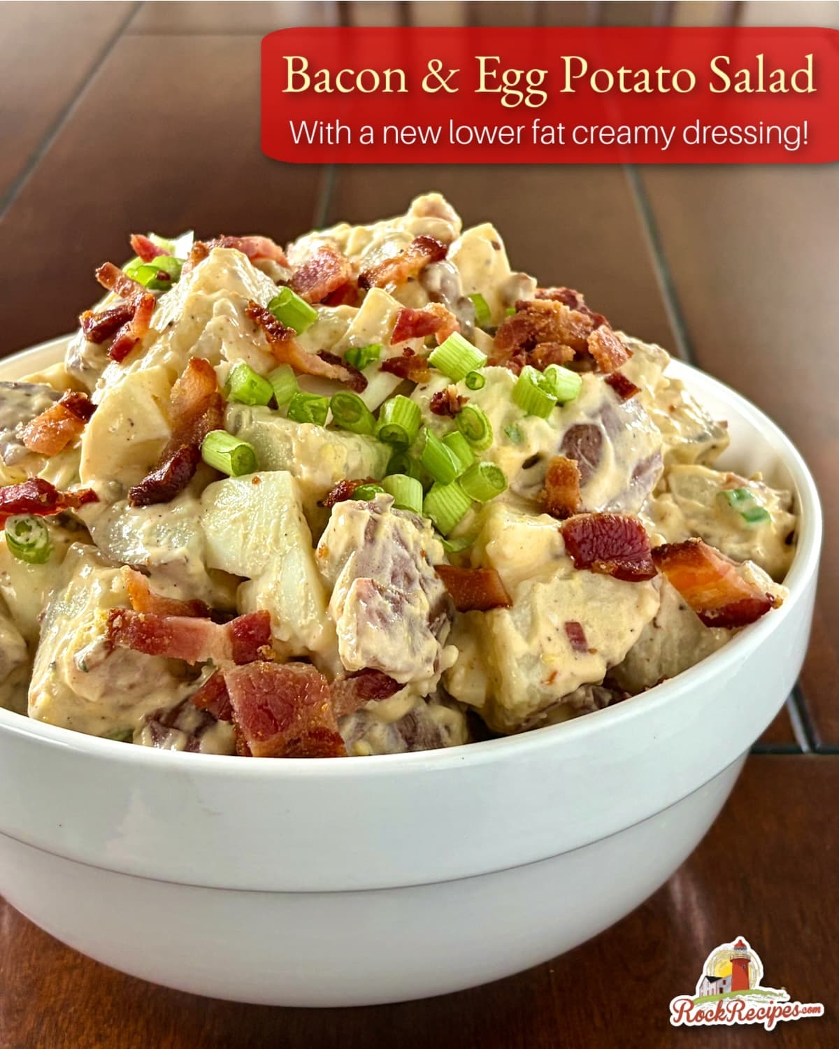 Bacon and egg potato salad in a white bowl with title text and rock recipes logo added for social media posts.