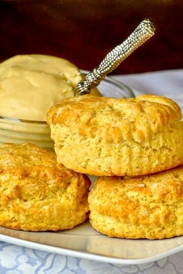 Corn Flour Biscuits with Maple Butter photo of biscuits stacked on a white plate with maple butter in the background.