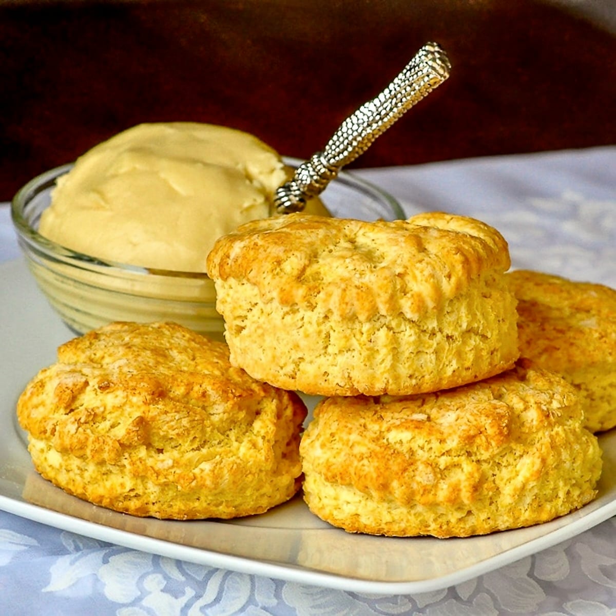 Corn Flour Biscuits with Maple Butter photo of biscuits stacked on a white plate with maple butter in the background.