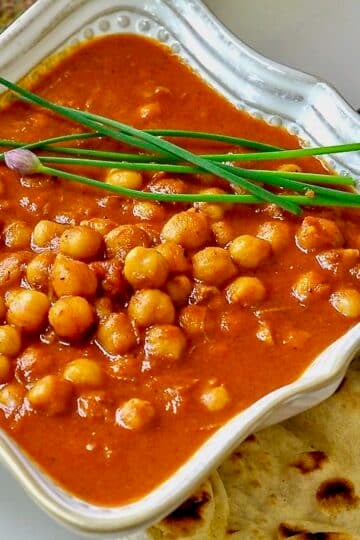 Easy Coconut Chickpea Korma single serving in a white bowl with naan on the side.