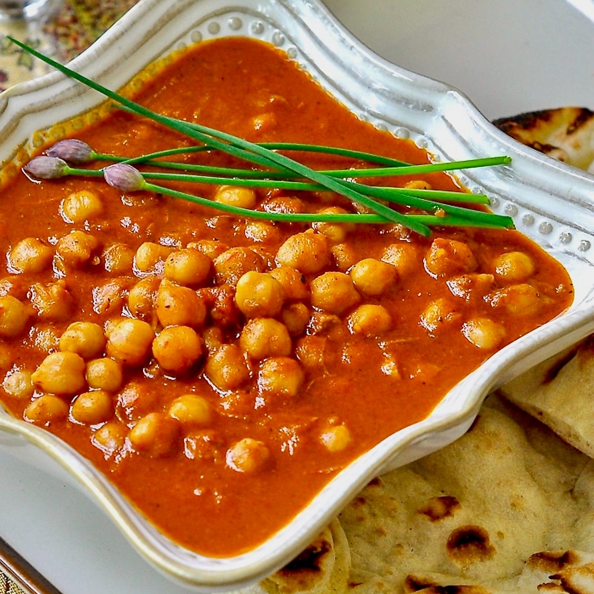 Easy Coconut Chickpea Korma single serving in a white bowl with naan on the side.