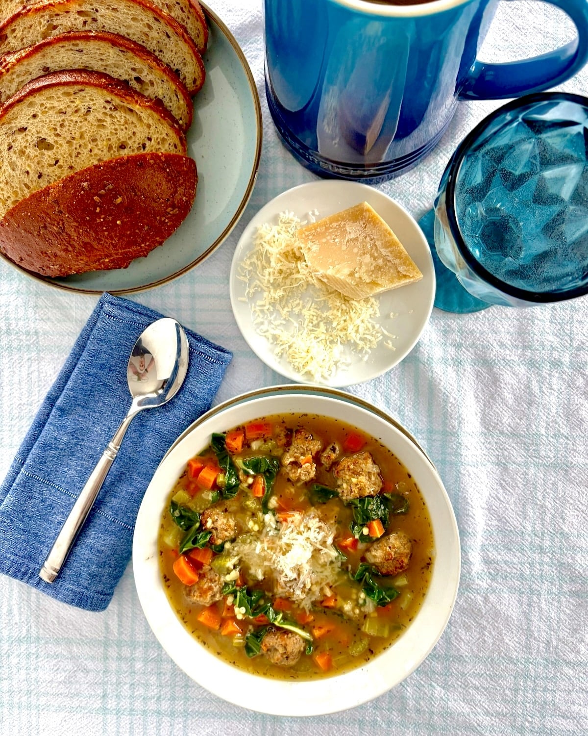 Overhead wide photograph shot with bread water and parmesan cheese and a spoon