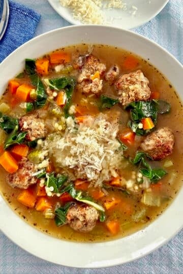 Overhead photo of one bowl of Italian wedding soup garnished with grated Parmesan original cheese shot for Google featured image