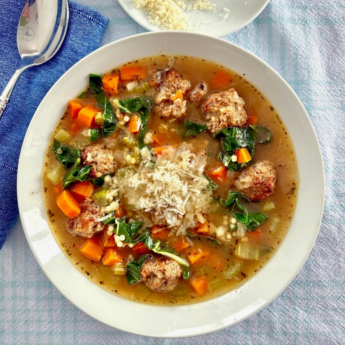 Overhead photo of one bowl of Italian wedding soup garnished with grated Parmesan original cheese shot for Google featured image
