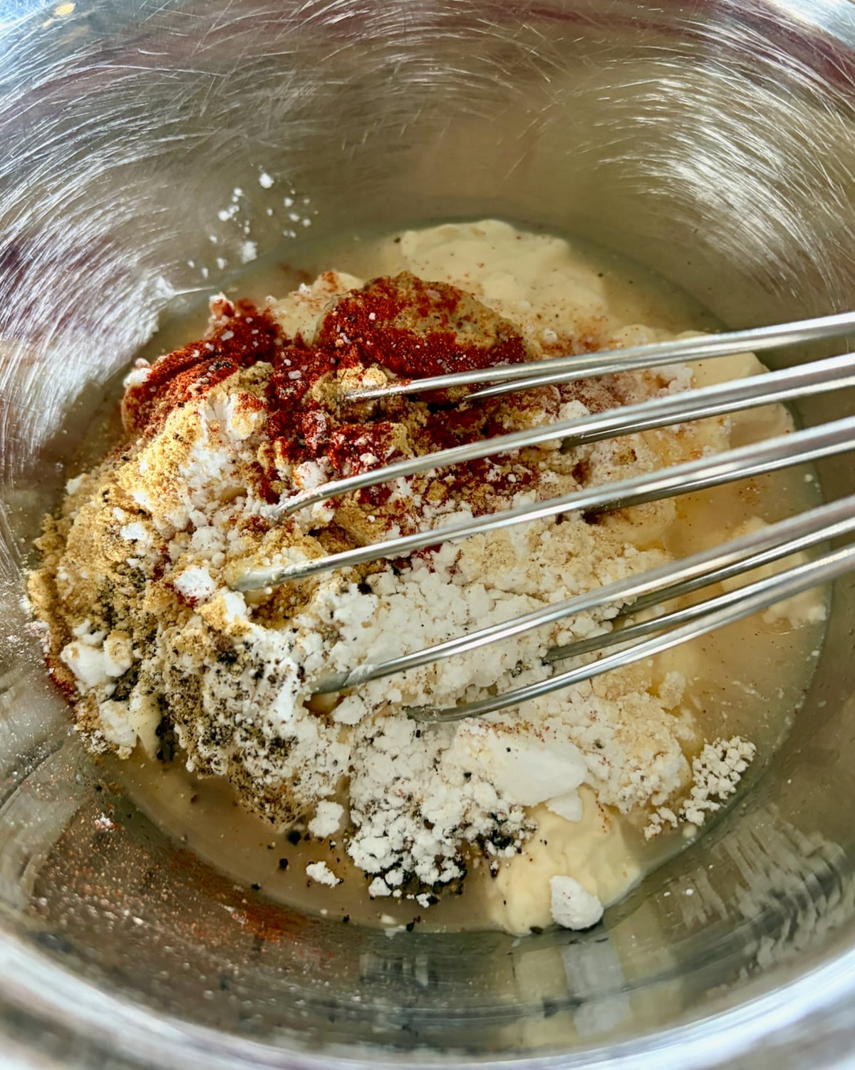 Ingredients for better than Miracle Whip salad dressing in a metal bowl with whisk.