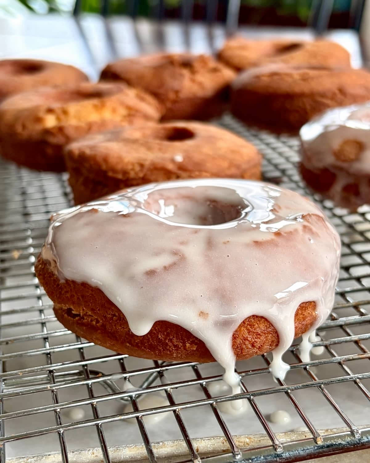 Close up photo of one sour cream donut with vanilla glaze dripping over the top