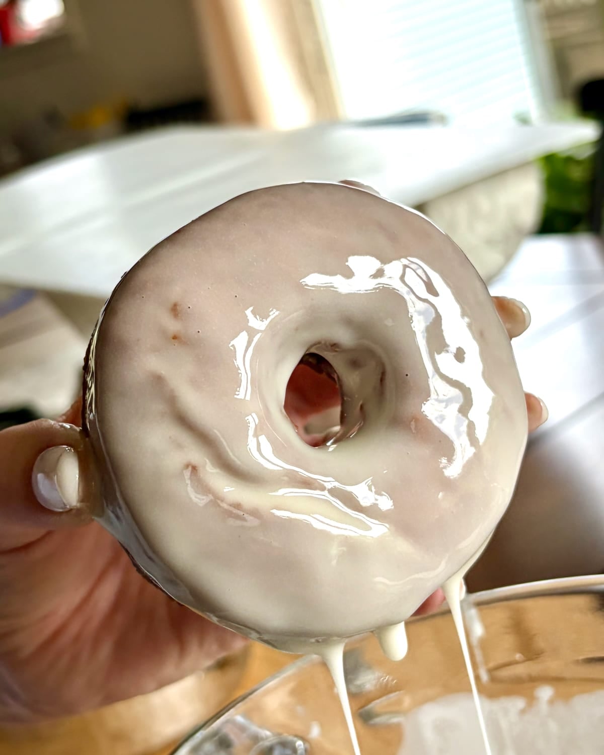 Photo of one donut immediately after being dipped into vanilla glaze.