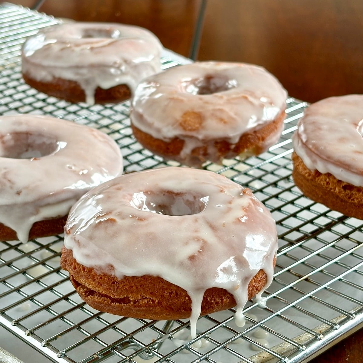 Vanilla glazed sour cream donuts cooling on a wire rack