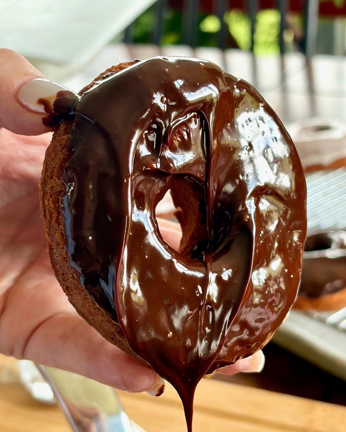 Photo of one donut showing chocolate glaze freshly dipped dripping from the donut.