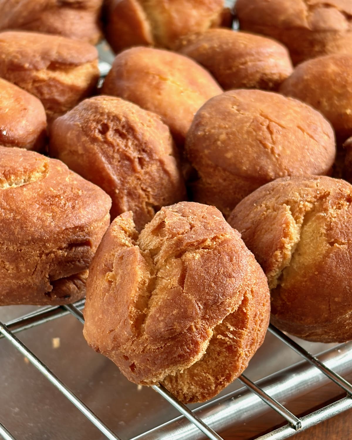 Photo of donut holes from sour cream donuts cooling on a wire rack.