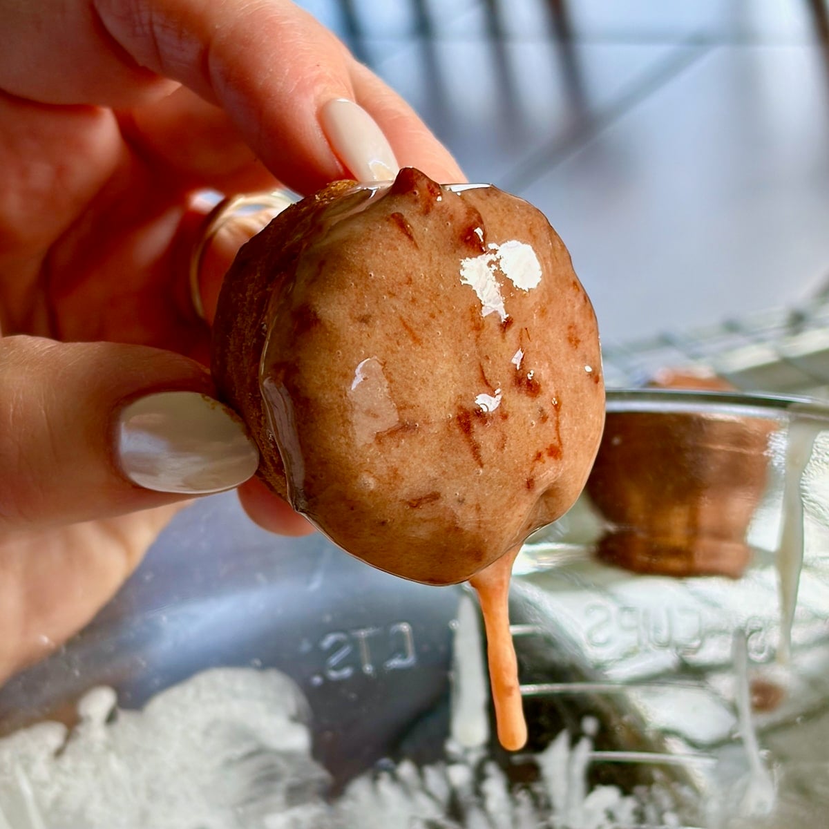 Photo of one donut hole after being dipped into strawberry glaze