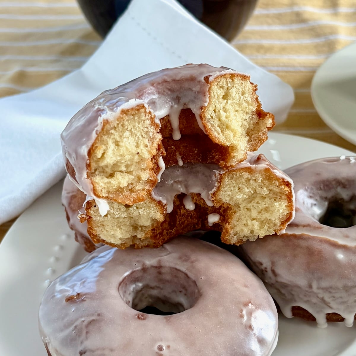 Photo of one vanilla glazed sour cream donut broken open to show interior crumb.