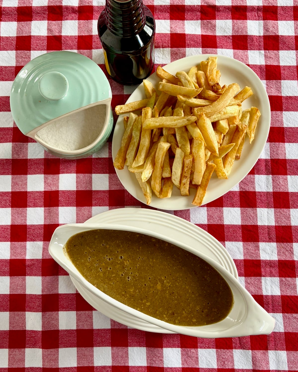 overhead photo of chicken skin gravy in a white gravy boat with french fries on the side!