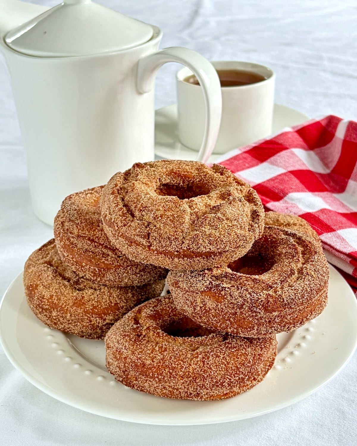 Cinnamon sugar donuts on a white plate with a coffee service in the background.