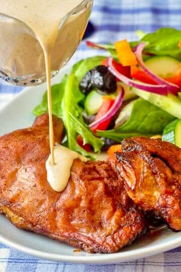 White Barbecue Sauce being poured over a plate of smoked chicken.
