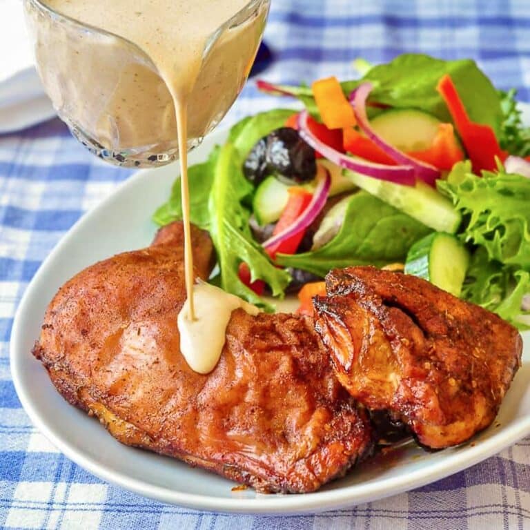 White Barbecue Sauce being poured over a plate of smoked chicken.