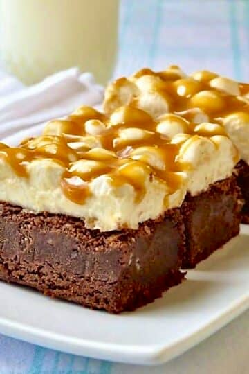 Caramel Marshmallow Brownies shown on a white plate with a glass of milk in the background.