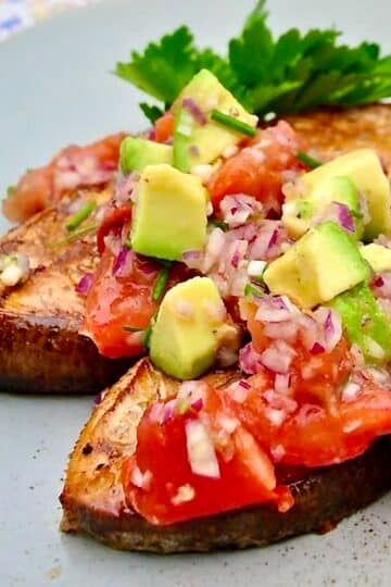 Cedar Plank Halibut with Charred Tomato Avocado Salsa, shown as a close up photo with two servings in a blur plate.