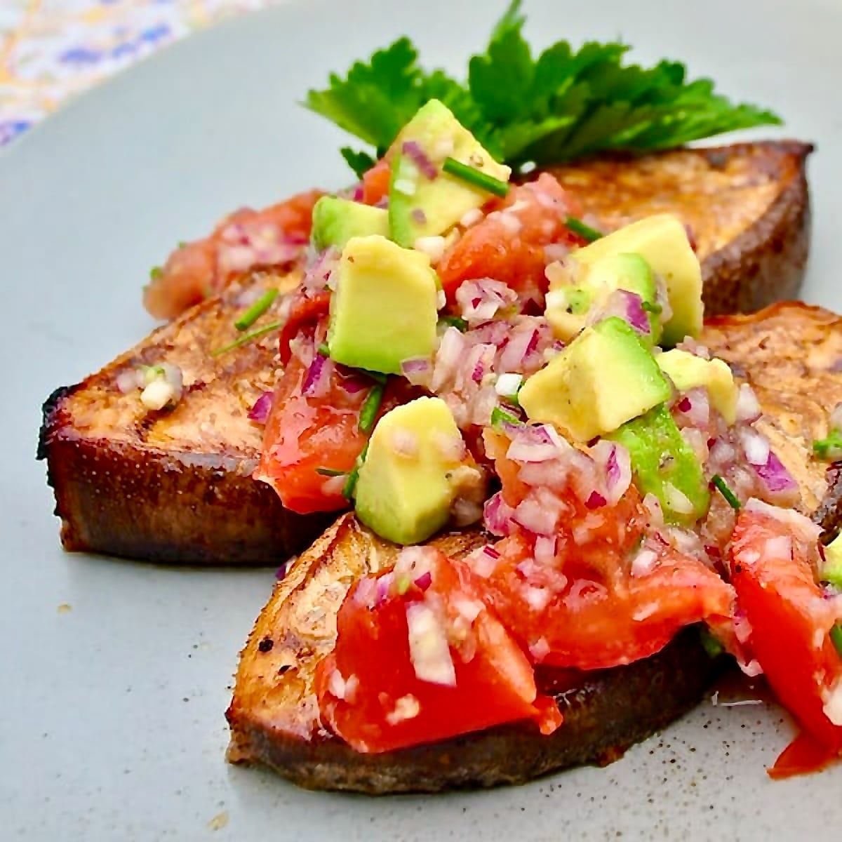 Cedar Plank Halibut with Charred Tomato Avocado Salsa, shown as a close up photo with two servings in a blur plate.