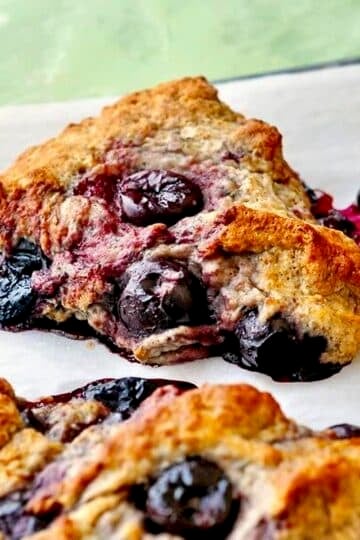 Cherry Spice Scones shown cooling in a parchment paper lined baking pan.