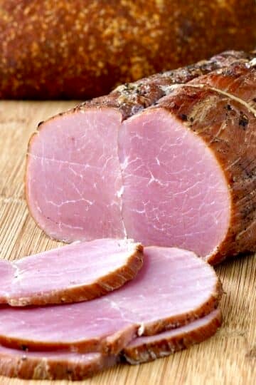 Photo of Homemade Tenderloin Ham sliced on a wooden cutting board.