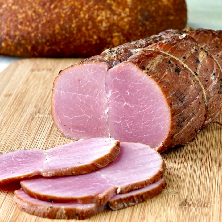 Photo of Homemade Tenderloin Ham sliced on a wooden cutting board.