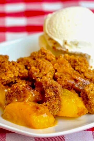 Ginger Snap Peach Crumble photo of a single serving on a white plate with vanilla ice cream.